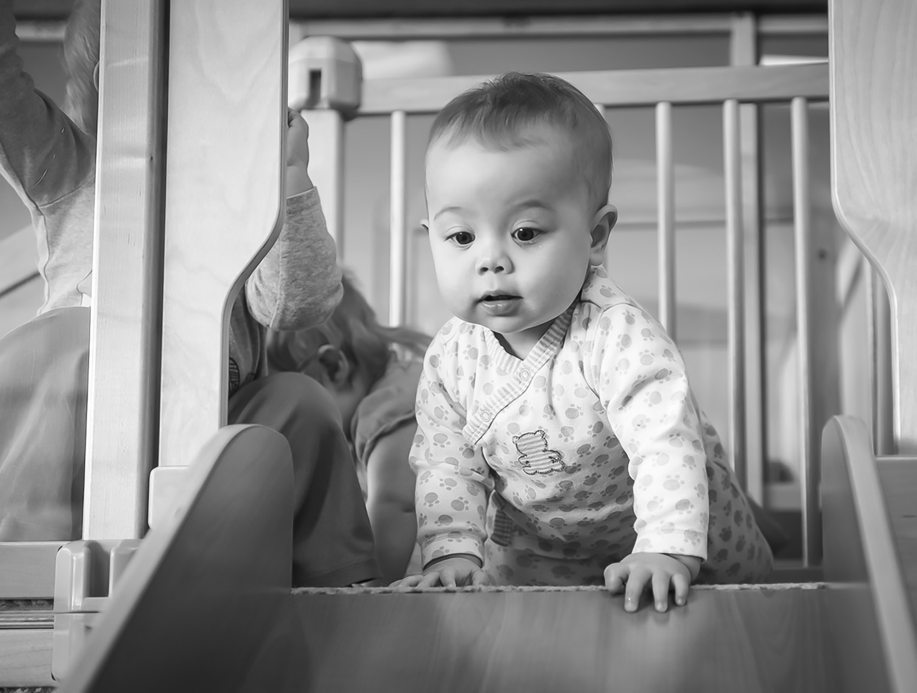 Black and white image of a baby at the top of a slide